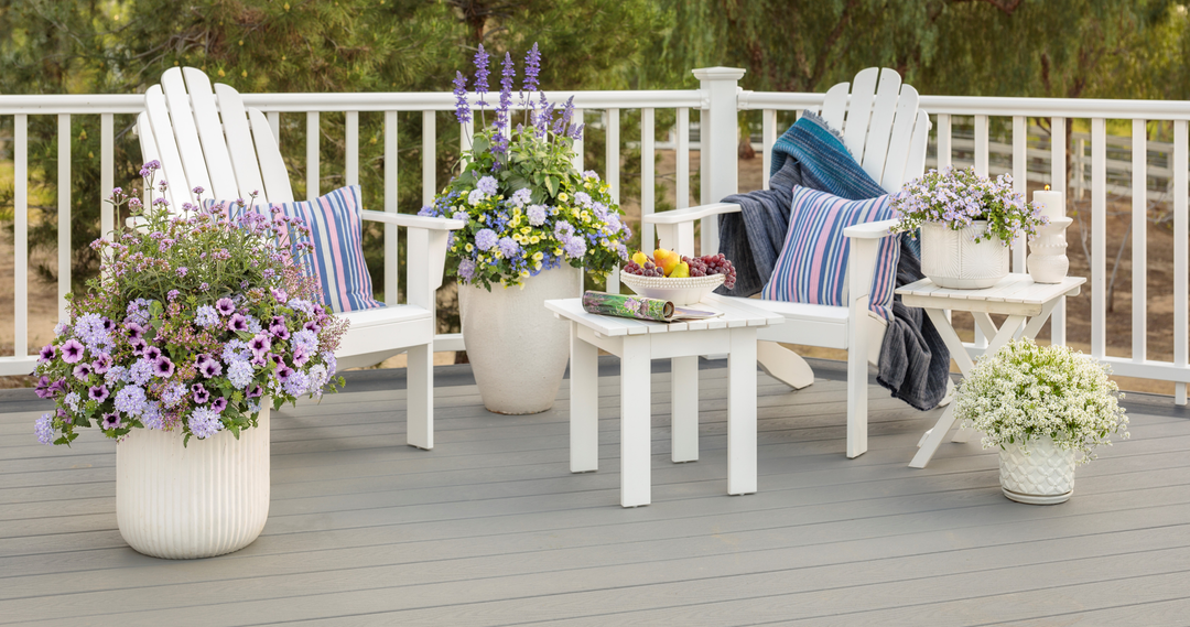 Scene of outdoor patio with white rails and white furniture next to white pots filled with colorful combination planters